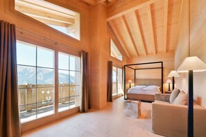 A spacious bedroom with a large window, a bed, a bedside table, and a view of mountains. - Ferienlenk Mountain Village (Lenk)