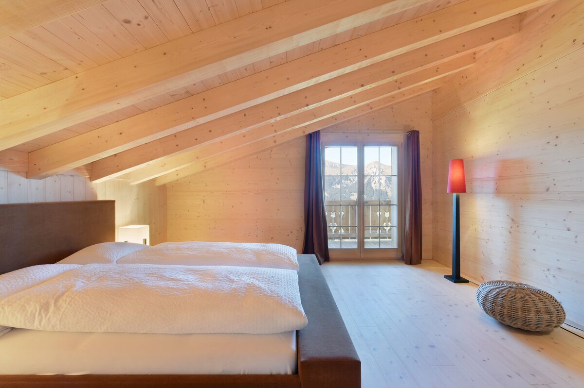 Un dormitorio con techo de madera, una cama grande, una ventana con vistas y una lámpara de pie roja.
