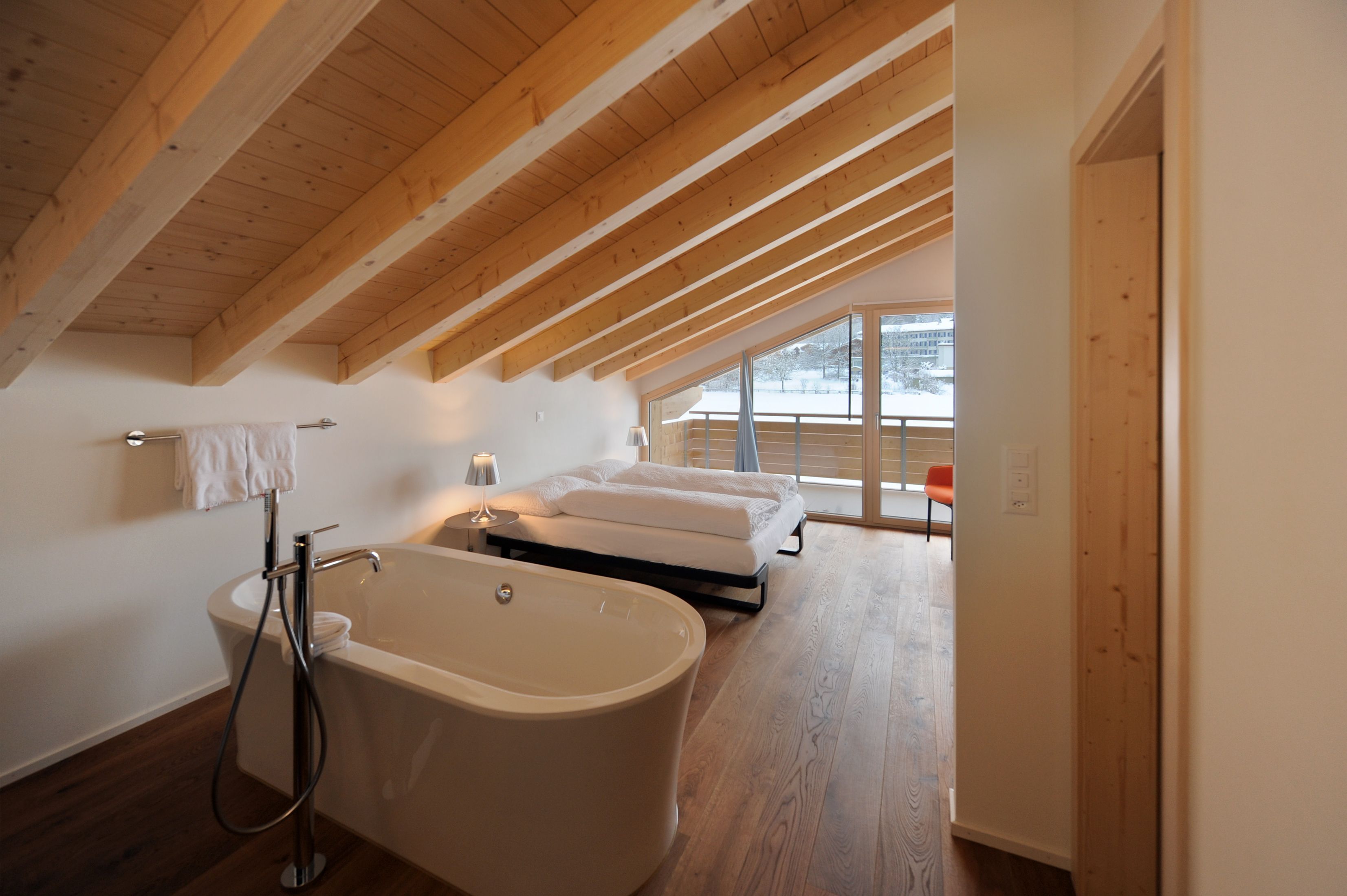 A modern bathroom with a freestanding bathtub, a towel rack, and a large window offering a view of the outdoors.