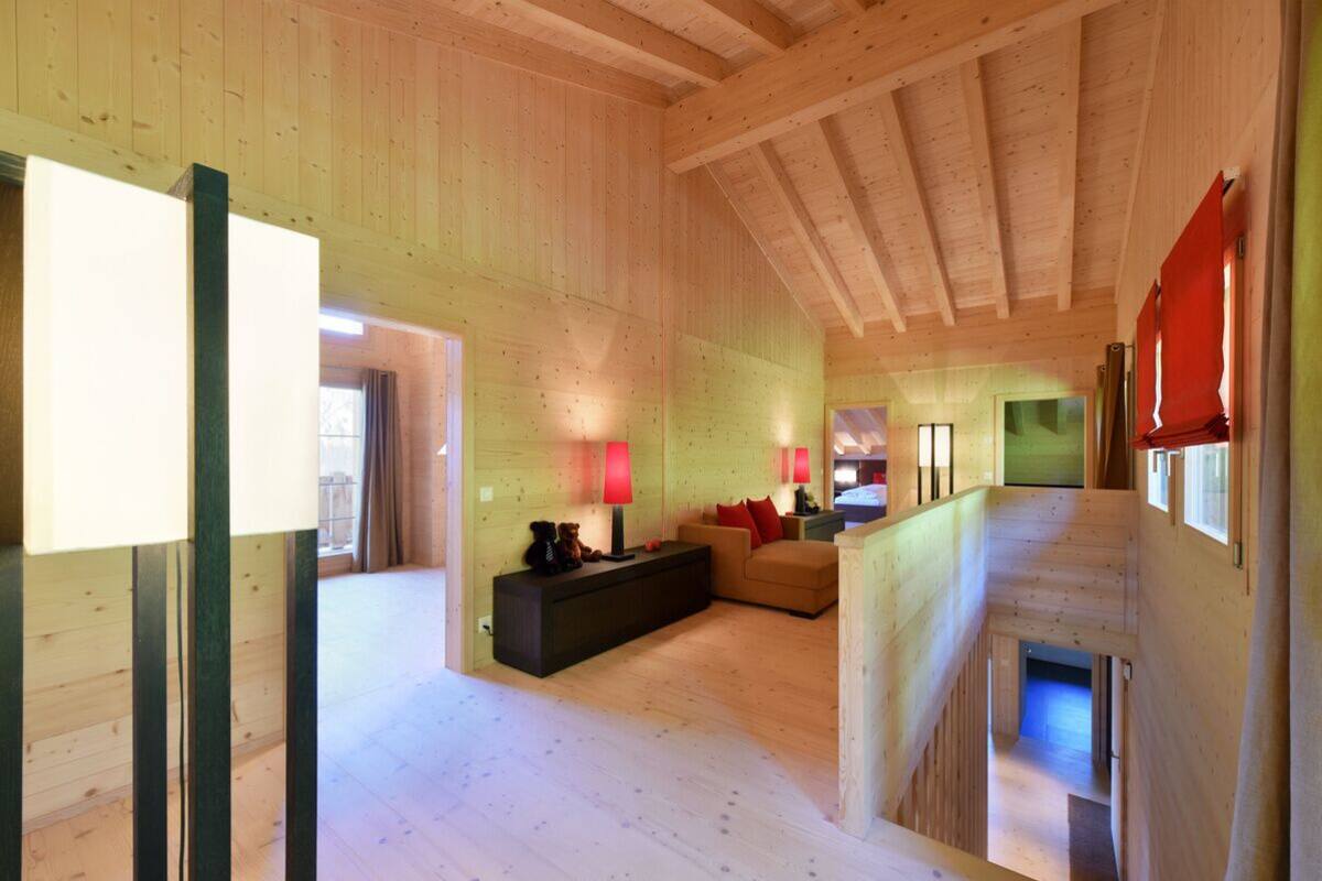 A spacious wooden interior with a sofa, a side table, and a lamp.