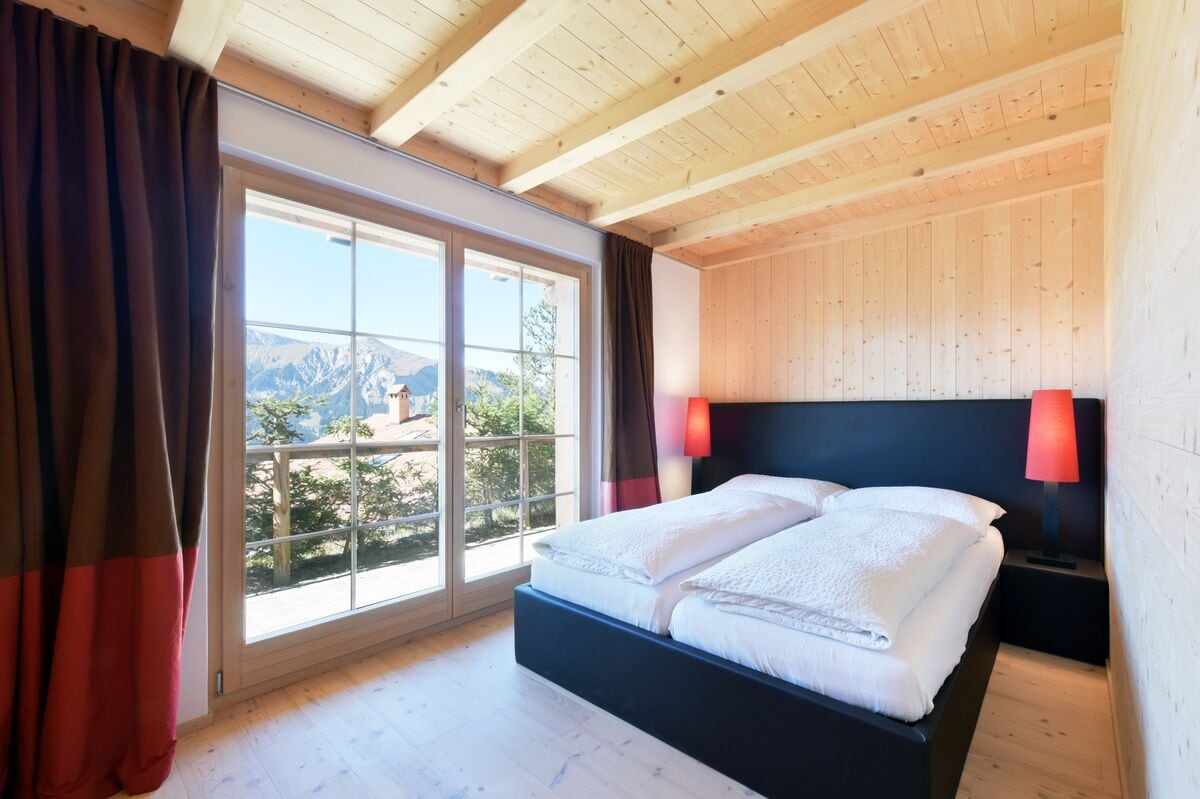 Een slaapkamer met een groot raam, een bed en houten wanden.