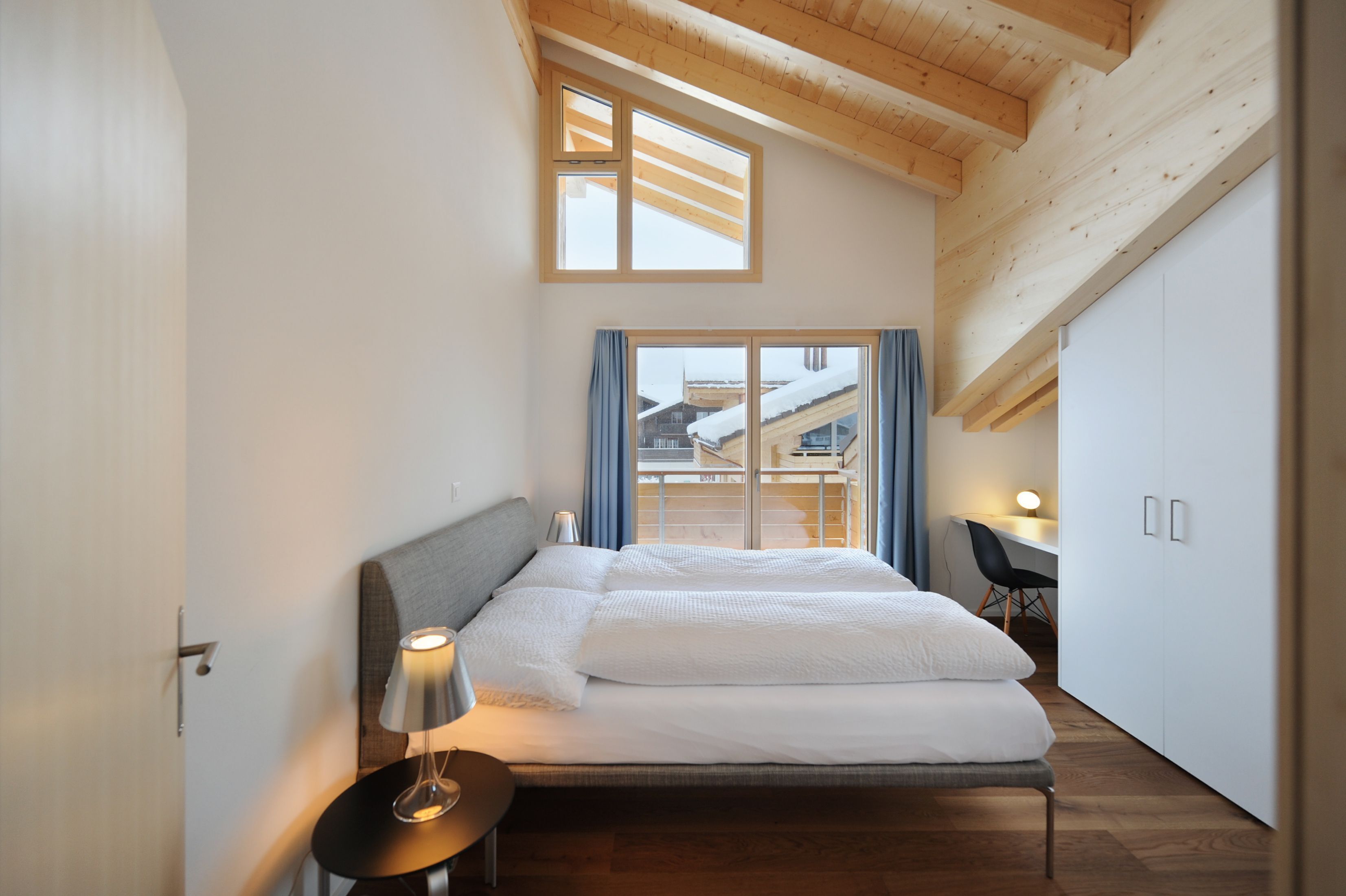 Une chambre moderne avec un grand lit, un bureau et une vue sur un paysage enneigé par la fenêtre.