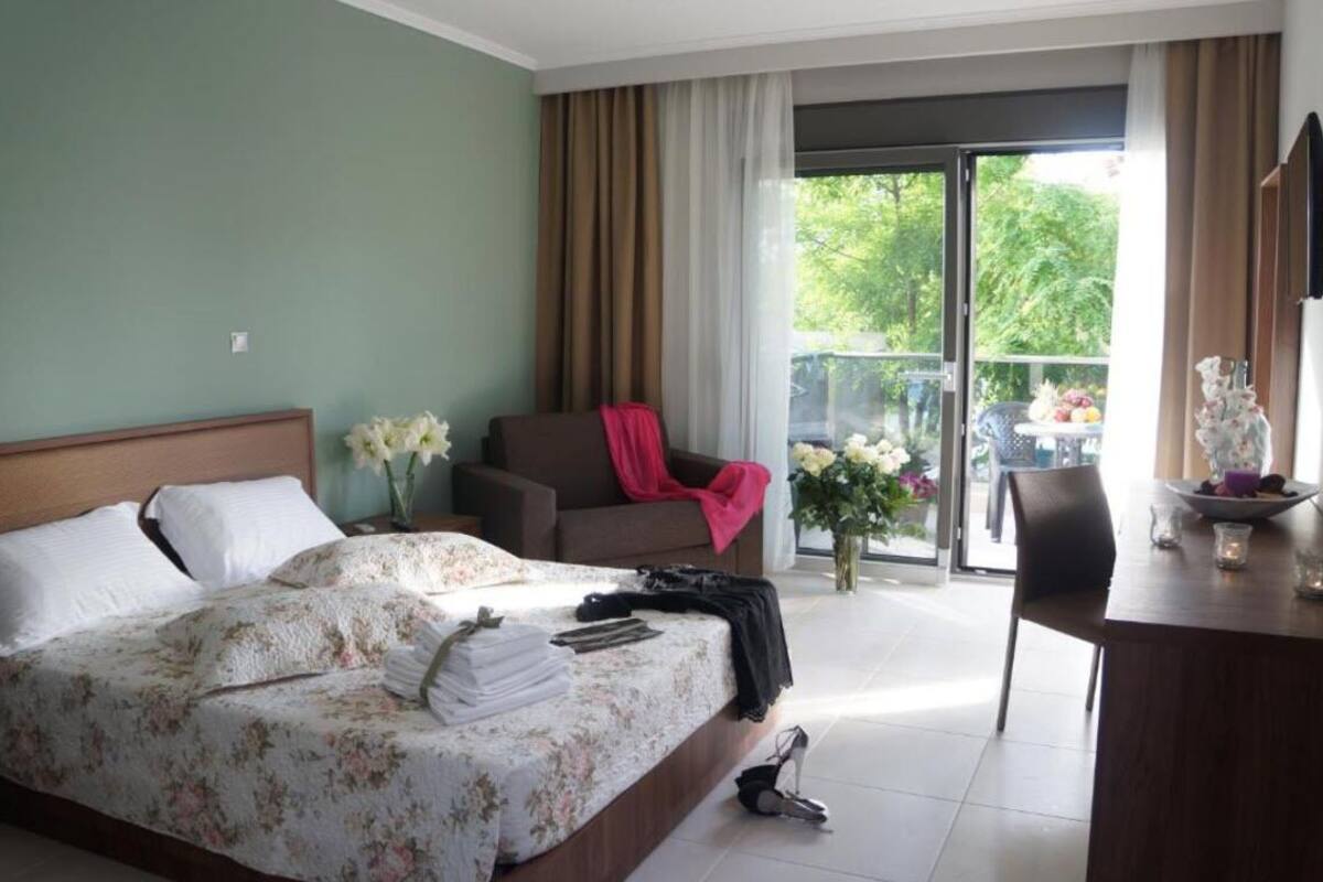 Une chambre d’hôtel avec un lit, une chaise, un bureau et un balcon donnant sur un paysage verdoyant.