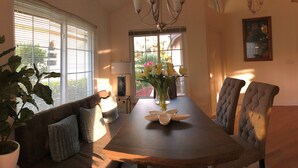 Un comedor con una mesa de madera, sillas acolchadas, un sofá y una planta en maceta.