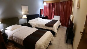 Une chambre d’hôtel avec deux lits, un bureau, une chaise, une lampe et un téléviseur.