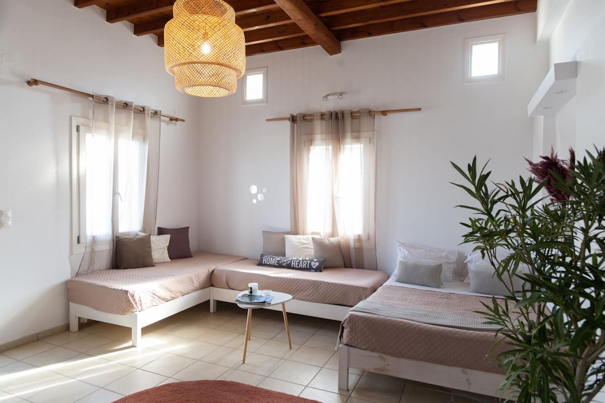 A cozy bedroom with two beds, a small table, and a hanging light fixture.