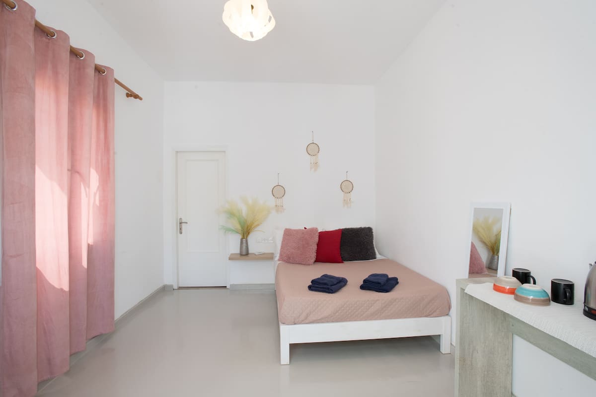 A bedroom with a bed, bedside table, and a mirror.