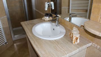 Un bagno con un lavandino bianco, uno specchio e una zona doccia.