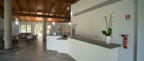 A spacious lobby with a high ceiling, a reception desk, and a fire extinguisher on the wall.