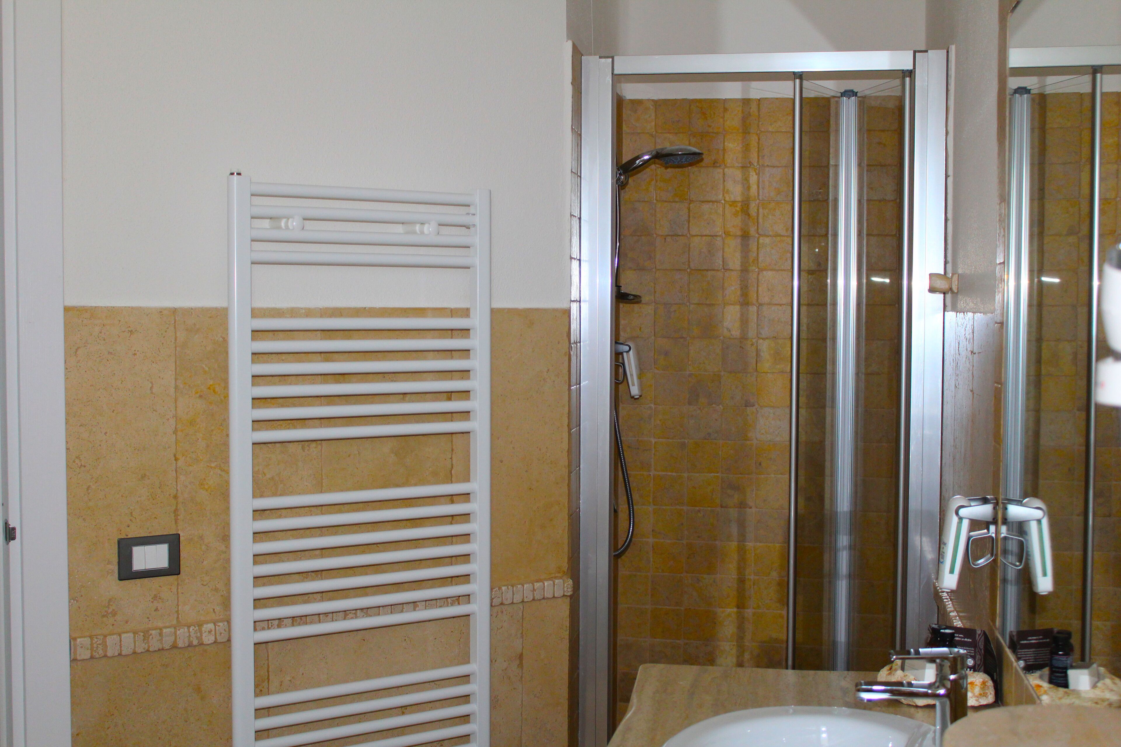 Een badkamer met een douche, een handdoekhouder en een wastafel.