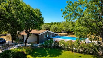 Una proprietà residenziale con piscina, un'auto parcheggiata davanti e un giardino curato.