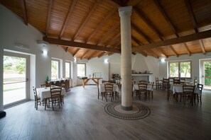 Une salle à manger spacieuse avec un plancher en bois, une colonne centrale et de nombreuses tables et chaises.
