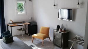 Une chambre moderne comprenant un lit, un bureau, une chaise, une télévision et une petite table avec une bouilloire.