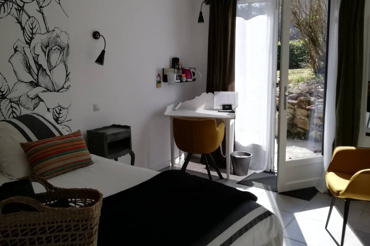 A bedroom with a bed, a desk, a chair, and a window with curtains.