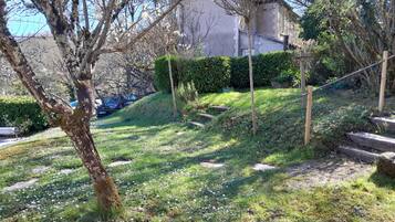 A residential area with a grassy slope, a tree, and a building in the background.