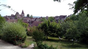 Un village historique à l’architecture traditionnelle, avec notamment une église dotée d’un clocher imposant, le tout entouré d’une végétation luxuriante et de bâtiments résidentiels.