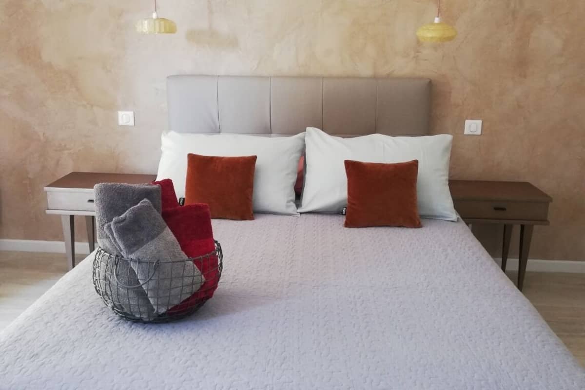 A bedroom with a bed, two bedside tables, a headboard, and two hanging lamps.