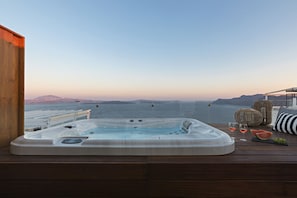 A hot tub on a wooden deck with a view of the sea and distant mountains. - 3 Elements by Stylish Stays (Santorini)