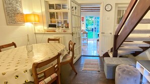 A cozy dining area with a round table, chairs, and a lamp. A staircase leads to a balcony with a view of the outdoors. - Bumblebee Cottage - a 19th Century Cottage in Area of Outstanding Natural Beauty (Gaddesden Row)
