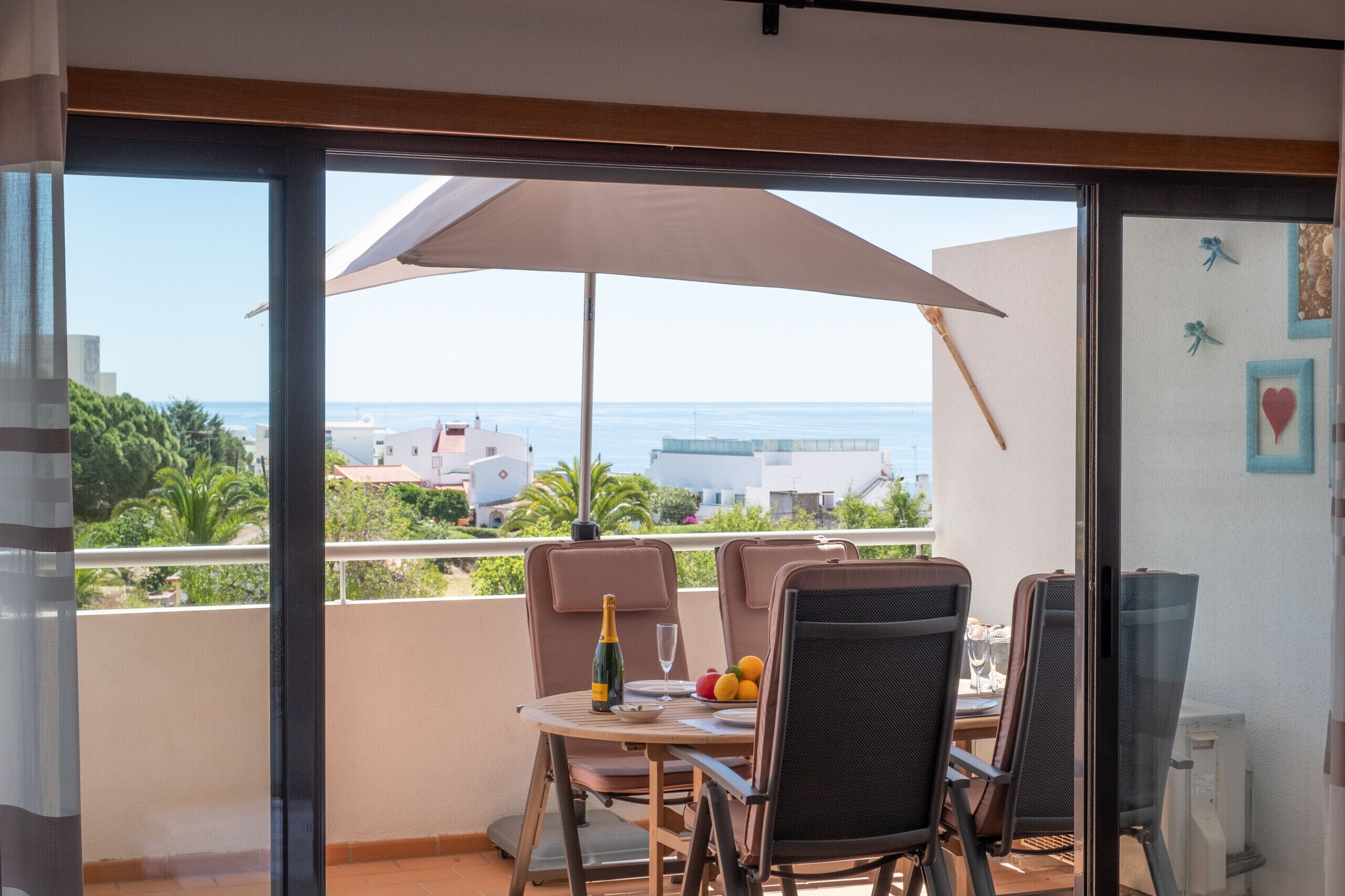 A balcony with a table set for two, a bottle of champagne, and a fruit bowl.