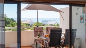 A balcony with a table set for two, a bottle of champagne, and a fruit bowl. - Comfortable sea view apartment [77] (Lagos)