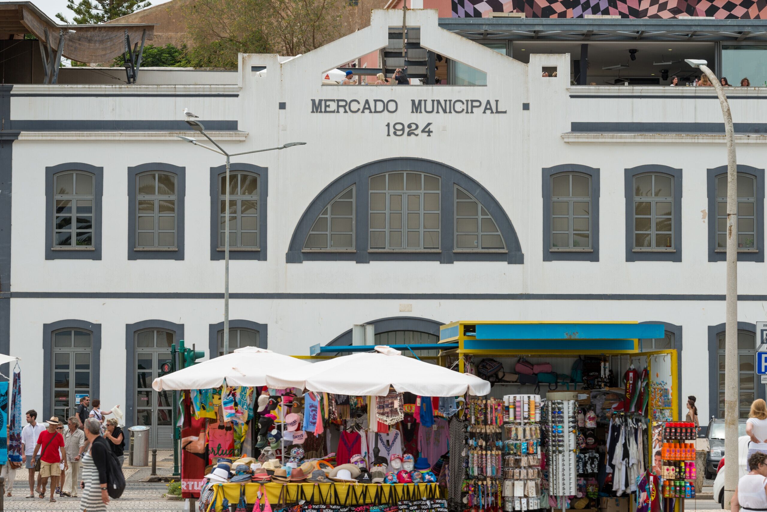 Ein historisches Gebäude mit der Aufschrift 'Mercado Municipal 1924', vor dem sich ein Marktstand befindet.