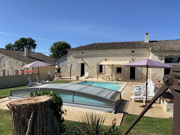 A stone house with a swimming pool, outdoor seating, and a barbecue area.