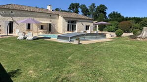 Ein Steinhaus mit Pool, Außenbereich und einem gepflegten Rasen.