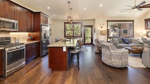 A spacious kitchen with dark wood cabinets, stainless steel appliances, and a central island with bar stools. - Near Keystone Village, Private Balcony & Large Windows with Mountain Views (Keystone)
