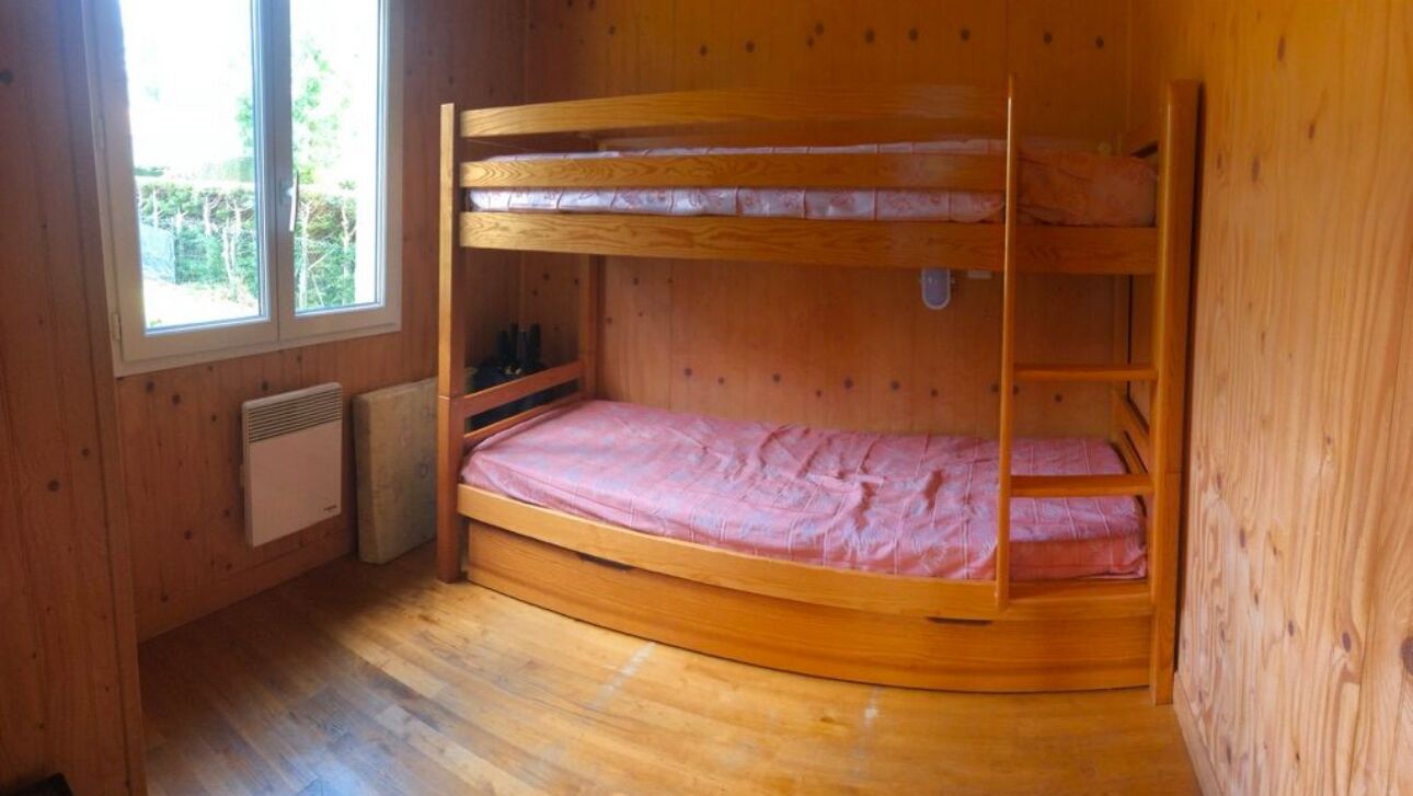 Une chambre avec un lit superposé, des murs en bois et une fenêtre.