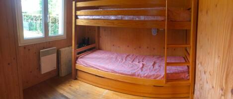 Une chambre avec un lit superposé, des murs en bois et une fenêtre.