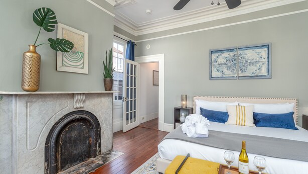A bedroom with a bed, a fireplace, a tray with wine glasses, and artwork on the walls.
