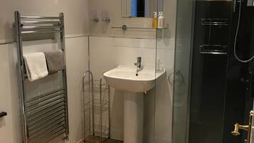 A modern bathroom with a glass shower enclosure, a pedestal sink, and a towel rack.