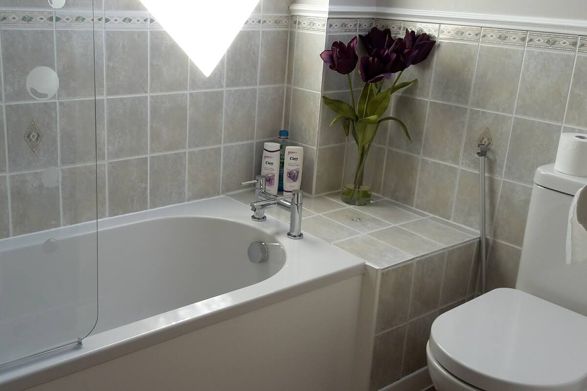 Ein Badezimmer mit einer Badewanne, Toilette und einer Vase mit Blumen.