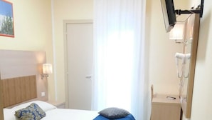 A hotel room with a bed, a small bedside table, a mirror, and a TV mounted on the wall. - Hotel Cuba Rimini (Rimini)