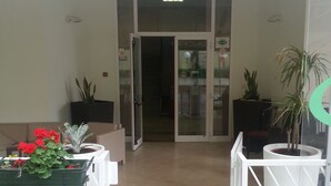 A reception area with a tiled floor, a white reception desk, and potted plants. - Hotel Cuba Rimini (Rimini)