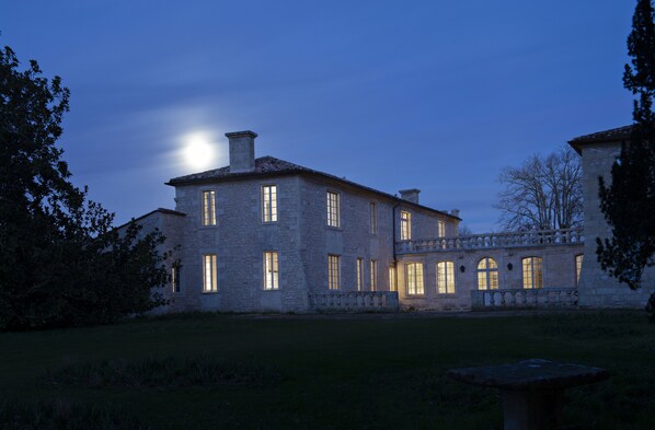 A large stone building with multiple windows and a central tower, surrounded by a well-maintained lawn and trees. - Château de Ferrand (Saint-Hippolyte)