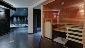 Een moderne spa met een sauna, een massagetafel en een ruime badkuip.
