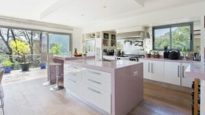 A modern kitchen with a large island, white cabinetry, and a view of the outdoors.