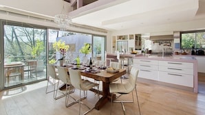 A modern kitchen with a large island, white cabinetry, and a dining area with a wooden table and chairs.