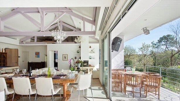 A dining area with a table set for four, a chandelier, and a view of the outdoors.