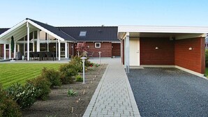 Un bâtiment doté d’un espace extérieur aménagé avec une zone de repos couverte, d’une allée en gravier et d’un jardin paysager.