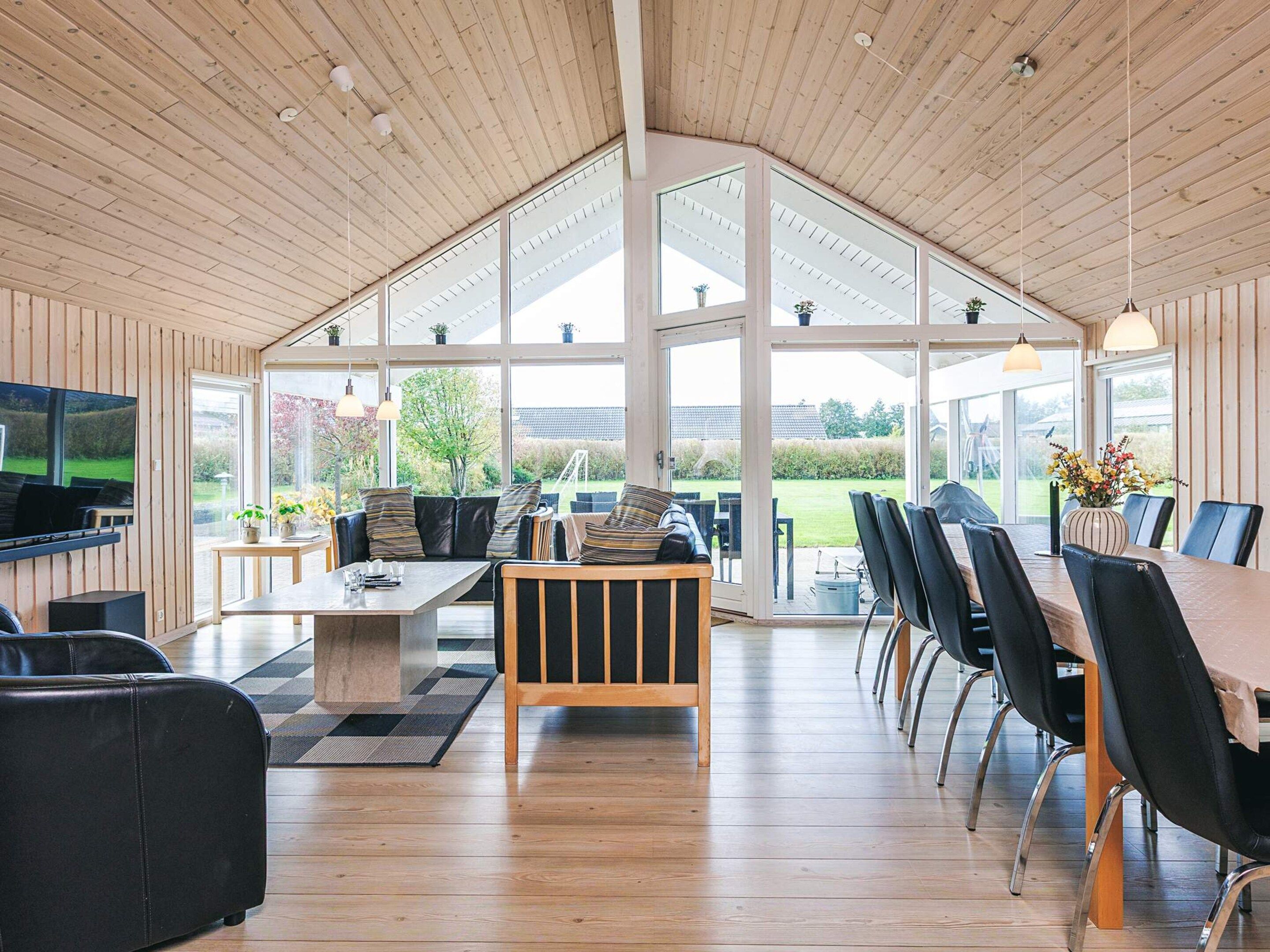 A spacious living area with a high ceiling, large windows, and a view of the outdoors.