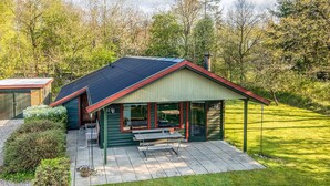 Uma casa com alpendre coberto, deck de madeira e pequeno jardim.