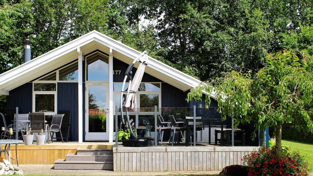 Una casa moderna con una terraza grande, mobiliario exterior y una chimenea.