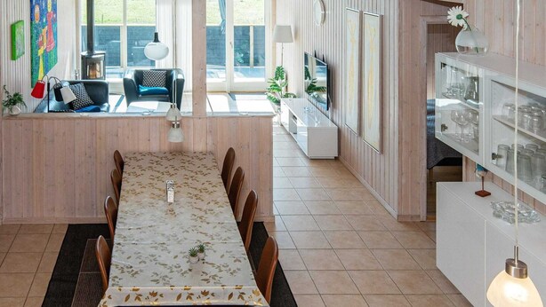 Een eethoek met een lange tafel, stoelen en een hanglamp.