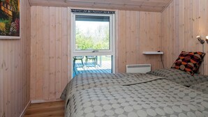 Een slaapkamer met een bed, een raam, een radiator en een schilderij aan de muur.