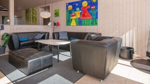 Een moderne woonkamer met een zithoek, een salontafel en een kleurrijk schilderij aan de muur.