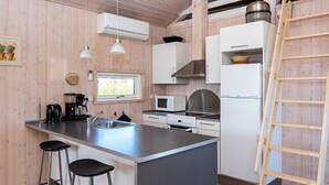 Een moderne keuken met houten wanden, een centraal kookeiland met krukken, een magnetron, een fornuis en een koelkast.