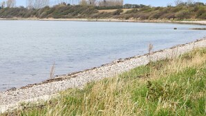 Un río tranquilo con orilla de guijarros y riberas cubiertas de hierba.